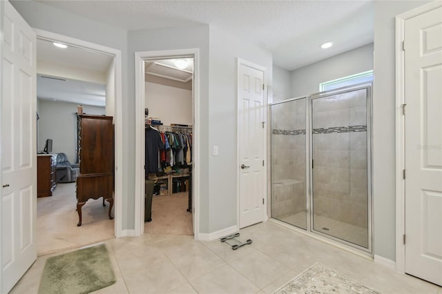 bathroom with a shower with shower door, a textured ceiling, and tile patterned flooring