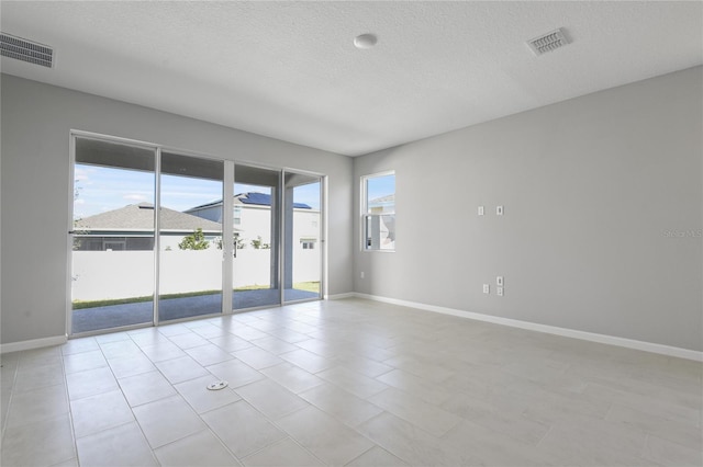 tiled empty room featuring a textured ceiling