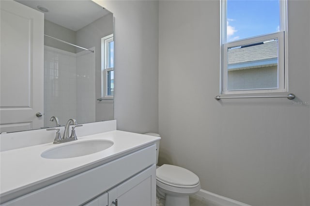 bathroom featuring vanity, a shower, a wealth of natural light, and toilet