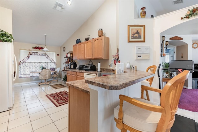 kitchen featuring light tile patterned flooring, sink, a kitchen breakfast bar, white refrigerator, and kitchen peninsula