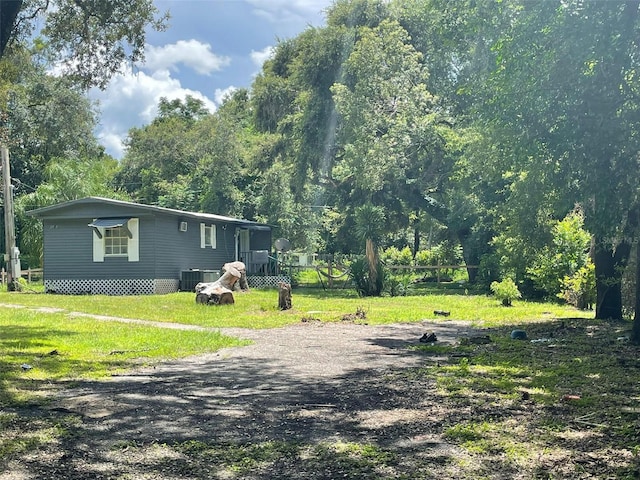 exterior space with cooling unit, driveway, and a front yard