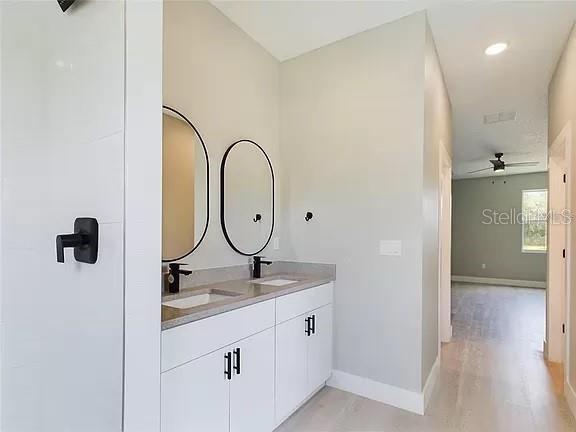 bathroom with double vanity, ceiling fan, and hardwood / wood-style flooring