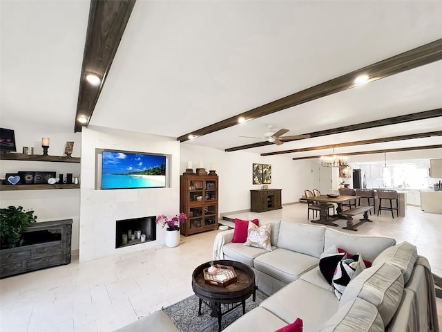 living area with beamed ceiling, a tiled fireplace, and ceiling fan