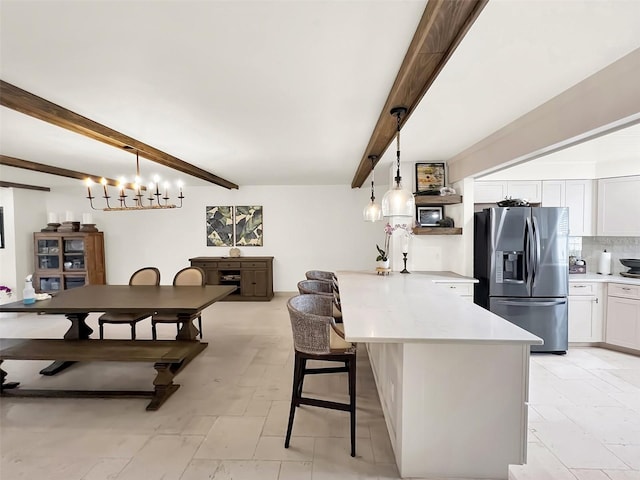 kitchen featuring a kitchen breakfast bar, a peninsula, light countertops, white cabinetry, and stainless steel refrigerator with ice dispenser