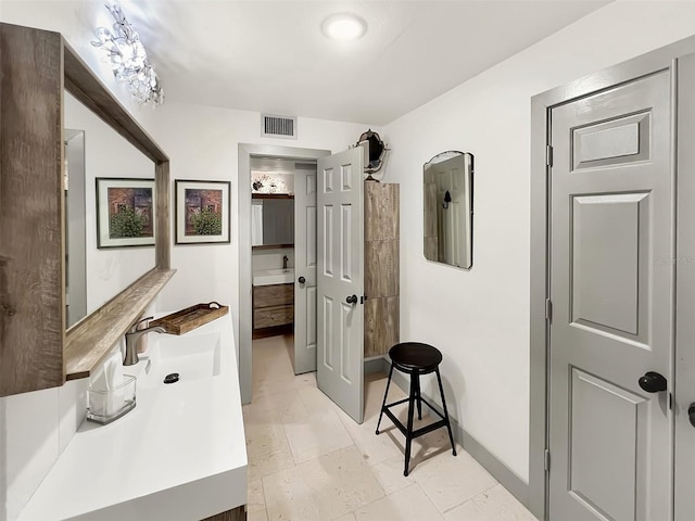 hallway with a sink, visible vents, and baseboards