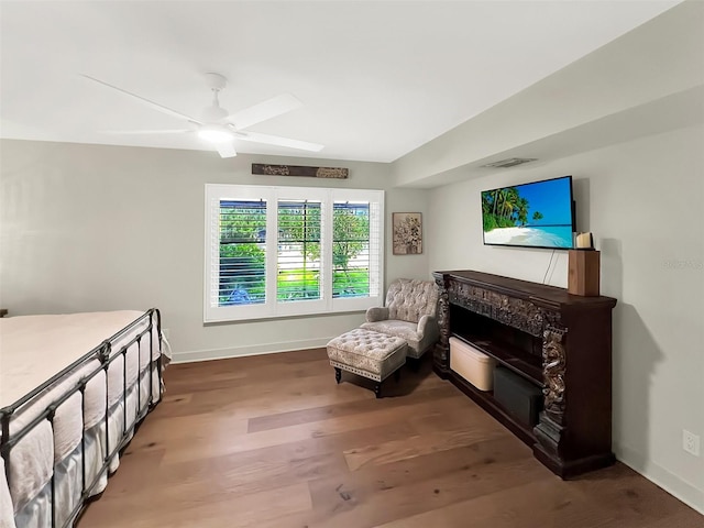 sitting room with a fireplace, visible vents, a ceiling fan, wood finished floors, and baseboards