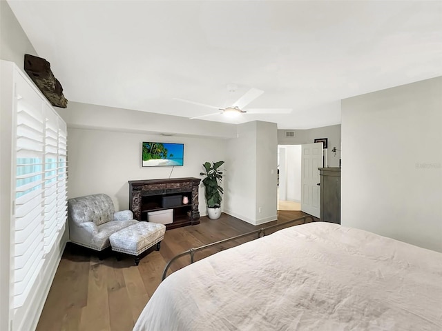 bedroom featuring baseboards, visible vents, a ceiling fan, wood finished floors, and a fireplace