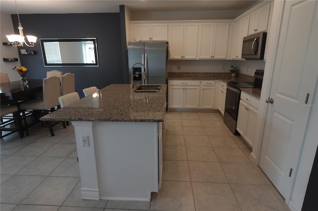 kitchen with appliances with stainless steel finishes, white cabinetry, sink, a kitchen island with sink, and light tile patterned flooring