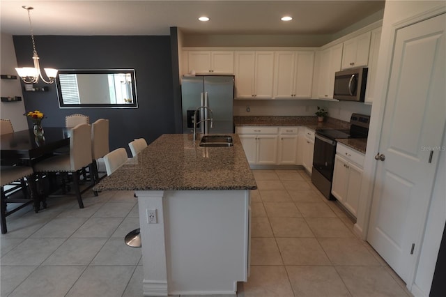 kitchen with light tile patterned flooring, stainless steel appliances, a center island with sink, and white cabinetry