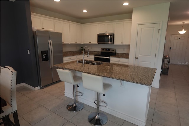 kitchen with appliances with stainless steel finishes, a center island with sink, and white cabinets