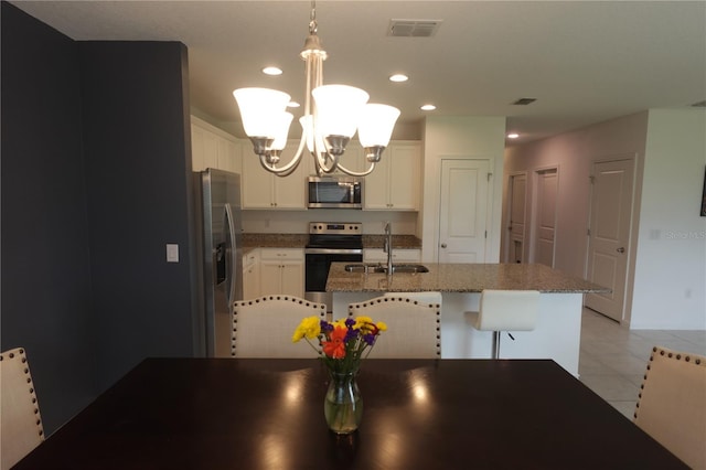 kitchen with appliances with stainless steel finishes, sink, white cabinets, light tile patterned flooring, and hanging light fixtures