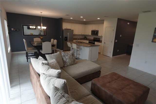 living room with sink, a notable chandelier, and light tile patterned flooring