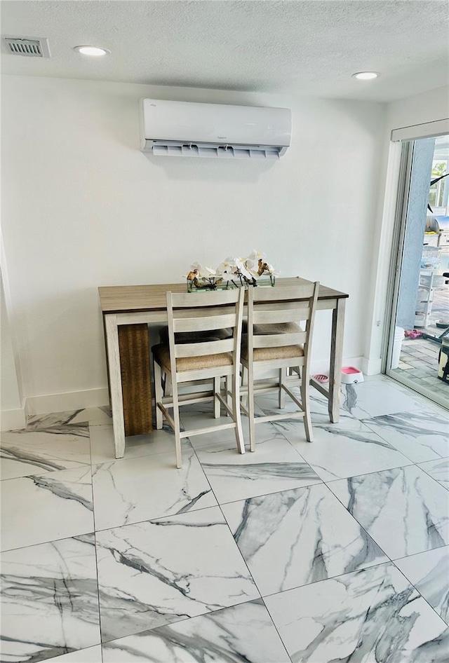 dining room featuring a wall mounted AC and a textured ceiling