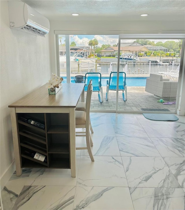 dining area featuring a wall mounted air conditioner and a textured ceiling