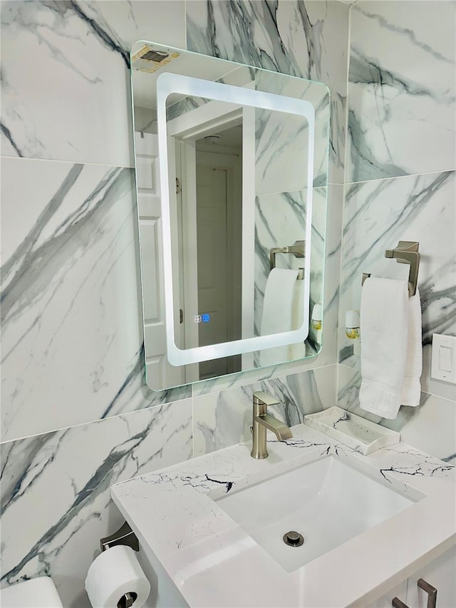 bathroom featuring vanity and tile walls