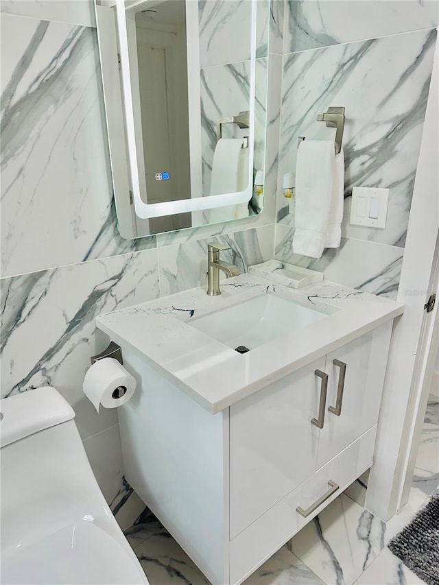 bathroom featuring vanity, tile walls, and toilet