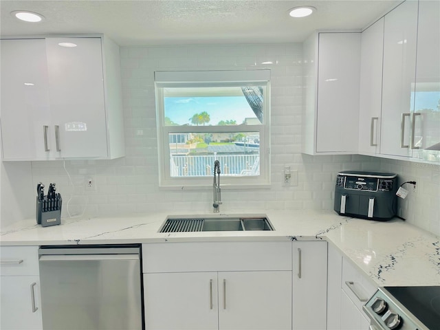 kitchen featuring sink, white cabinets, decorative backsplash, light stone counters, and stainless steel appliances