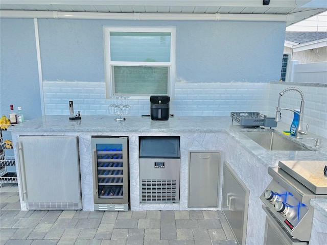 view of patio with an outdoor kitchen, sink, and beverage cooler