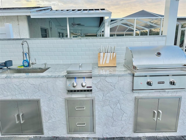 patio terrace at dusk featuring area for grilling, sink, grilling area, and glass enclosure