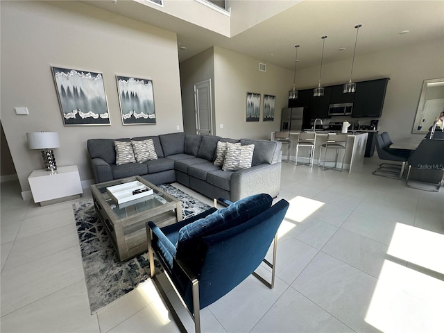 living room with sink, light tile patterned floors, and a towering ceiling