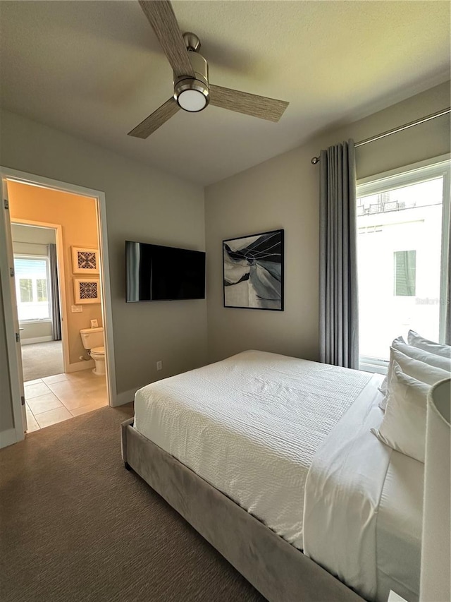 bedroom featuring baseboards, light colored carpet, light tile patterned floors, ensuite bathroom, and a ceiling fan