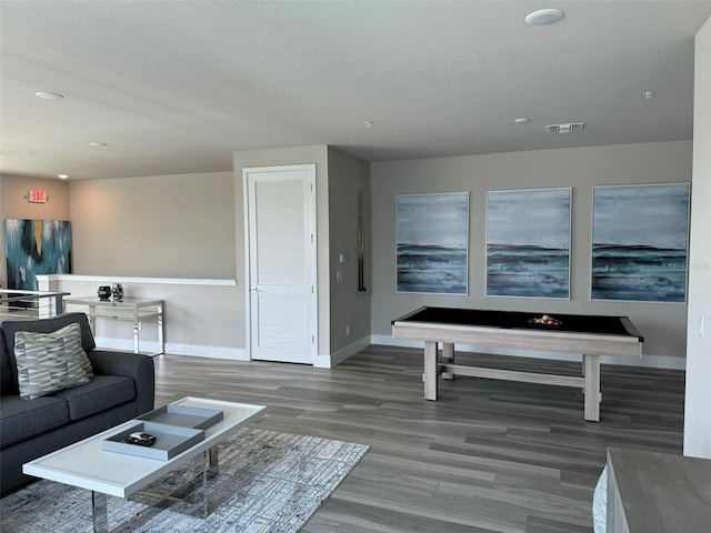 living area with visible vents, baseboards, a textured ceiling, and wood finished floors