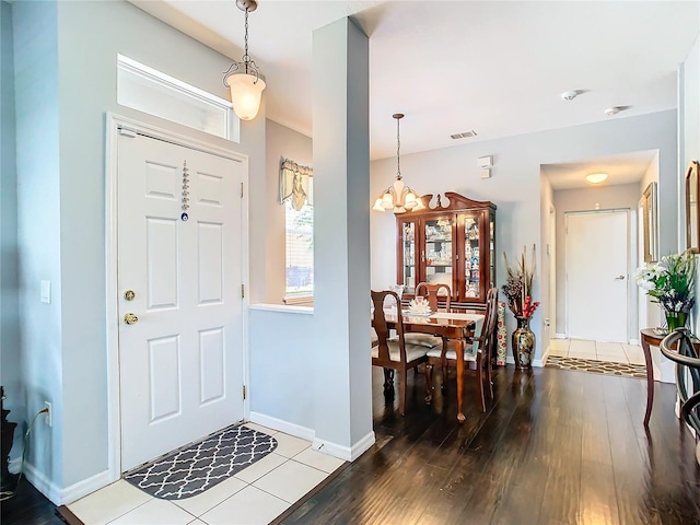 foyer entrance featuring a chandelier, wood finished floors, visible vents, and baseboards