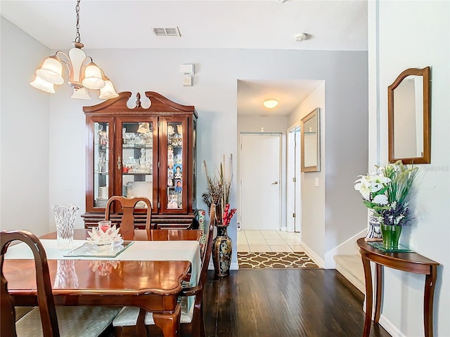 dining space with visible vents, a notable chandelier, baseboards, and wood finished floors