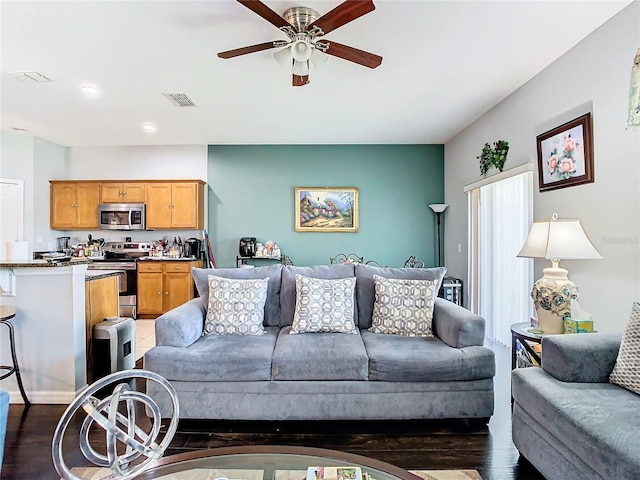 living area with dark wood finished floors, visible vents, and ceiling fan