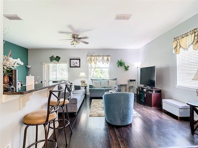 living area featuring dark wood-type flooring, visible vents, and ceiling fan