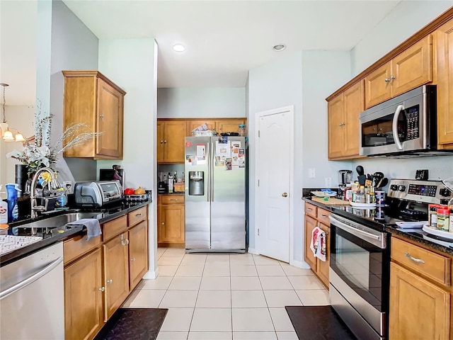 kitchen featuring decorative light fixtures, light tile patterned floors, appliances with stainless steel finishes, a sink, and dark stone counters