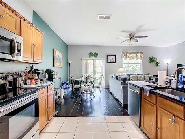 kitchen featuring light tile patterned floors, visible vents, open floor plan, appliances with stainless steel finishes, and dark countertops