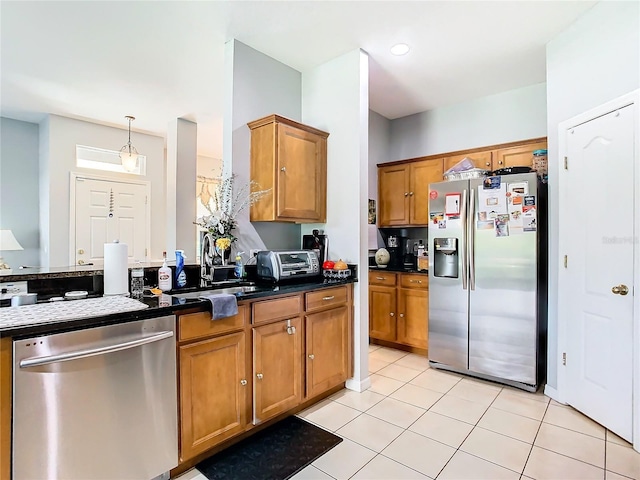 kitchen with dark countertops, brown cabinetry, stainless steel appliances, and a sink