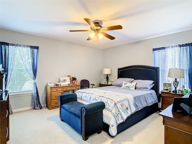 bedroom with a ceiling fan, light colored carpet, and baseboards