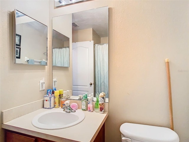 full bath with visible vents, vanity, and toilet