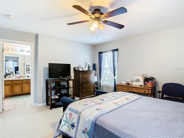 bedroom featuring ensuite bath, baseboards, a ceiling fan, and light colored carpet