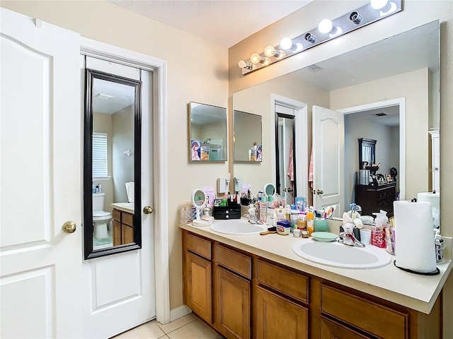 full bathroom featuring double vanity, a sink, toilet, and tile patterned floors