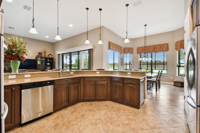 kitchen with light tile patterned flooring, sink, dark brown cabinets, hanging light fixtures, and appliances with stainless steel finishes