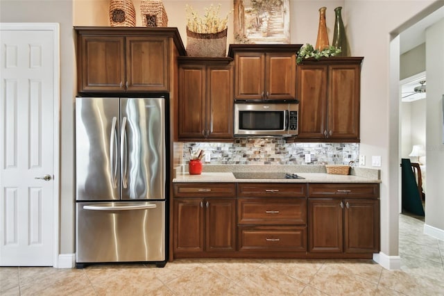 kitchen with light stone counters, appliances with stainless steel finishes, decorative backsplash, and light tile patterned floors