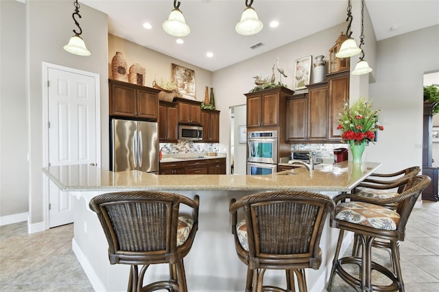 kitchen featuring appliances with stainless steel finishes, a breakfast bar, pendant lighting, and backsplash