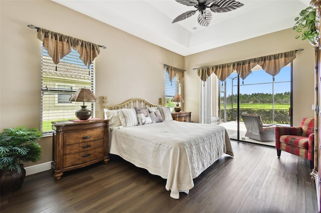 bedroom featuring ceiling fan, access to exterior, dark hardwood / wood-style flooring, and a raised ceiling