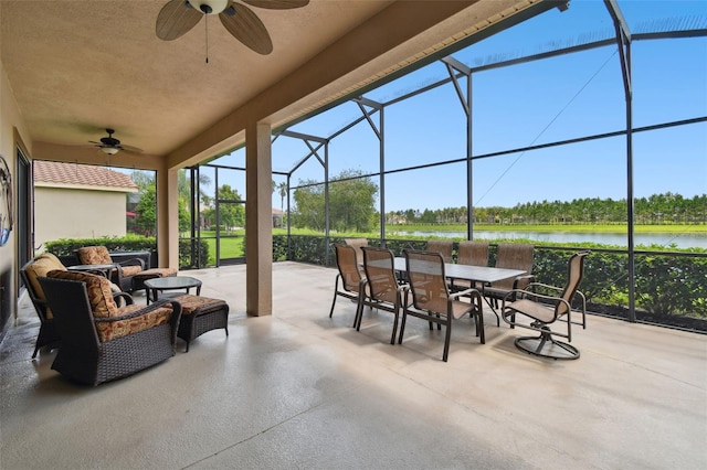 view of patio / terrace featuring ceiling fan, glass enclosure, and a water view