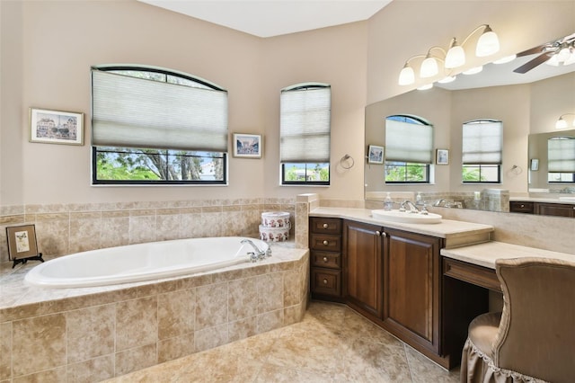 bathroom with tiled tub, vanity, a wealth of natural light, and ceiling fan