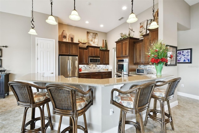 kitchen with tasteful backsplash, decorative light fixtures, a breakfast bar area, and appliances with stainless steel finishes