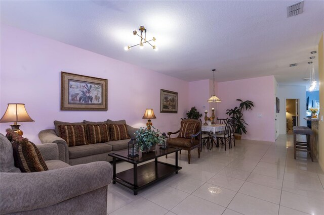 tiled living room with a notable chandelier