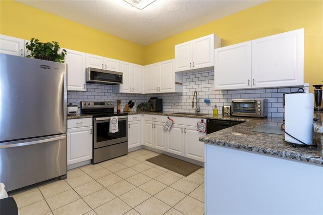 kitchen featuring stainless steel appliances, light tile patterned floors, sink, backsplash, and white cabinetry