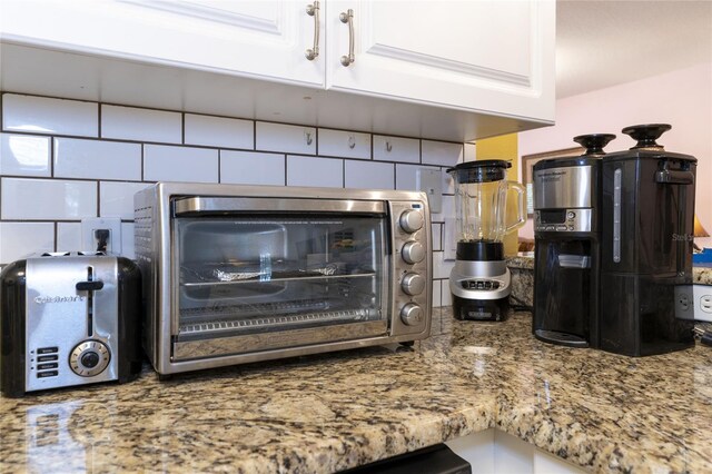 room details with tasteful backsplash, stone countertops, and white cabinetry