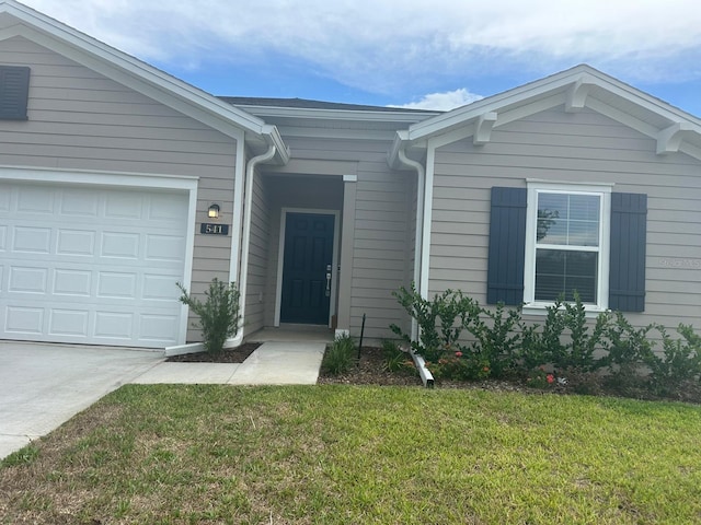 view of exterior entry with a garage and a yard