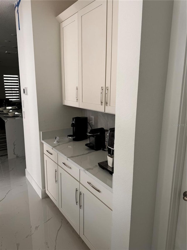 kitchen with light tile patterned flooring, white cabinetry, and light stone countertops