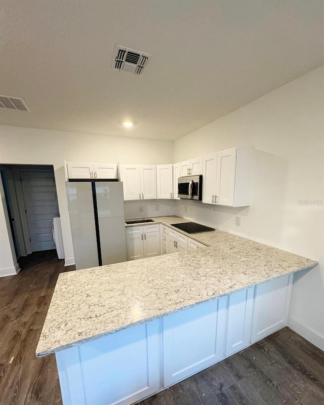 kitchen with white cabinetry, dark wood-type flooring, light stone countertops, and appliances with stainless steel finishes